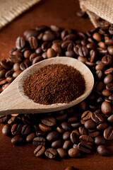 coffee powder (ground), on wooden spoon, coffee beans, with raffia cloth bag, brown background