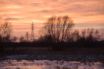 Pillars of a high-voltage power line in the fields in late autumn against the sunset