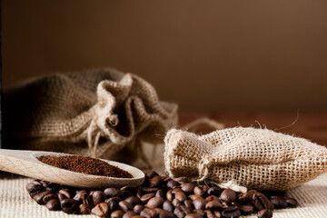 coffee powder (ground), on wooden spoon, with raffia cloth bag, brown background