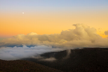 Fototapeta na wymiar The moon and fog banks sit over the Blue Ridge Mountains of North Carolina.