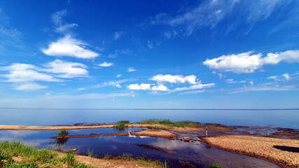 On the shore of the lake.  The calm water merges with the sky.