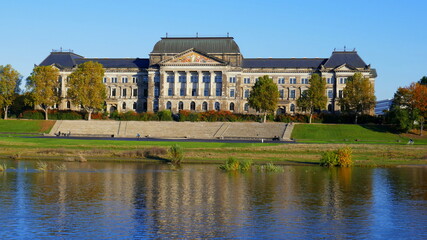 Fototapeta na wymiar Gebäude des Finanzministeriums von Sachsen in Dresden spiegelt sich in der Elbe bei blauem Himmel