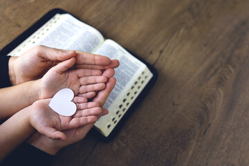 Religious Christian girl praying with her mother indoors