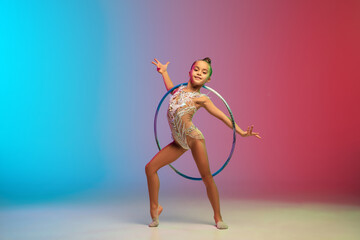 Tender. Little caucasian girl, rhytmic gymnast training, performing isolated on gradient blue-red...