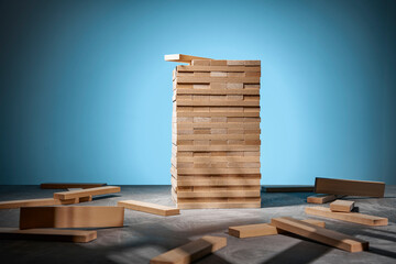 Tower of wooden blocks on a blue background and randomly lying wooden blocks