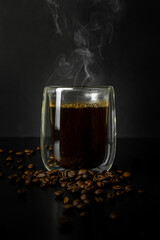 Freshly brewed steaming coffee in a glass Cup. Black background. Close up