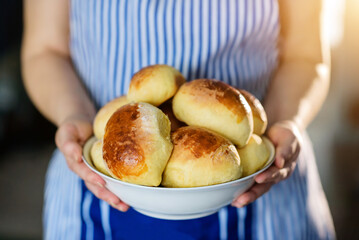 A dish with homemade pies in female hands close-up.