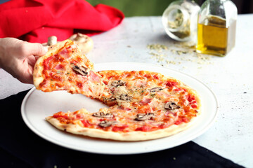 Hand grabs a slice of a whole pizza. Decoration with colors of the flag of italy