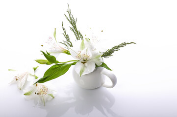 A bouquet of white flowers in a white vase on a glossy background. Alstrameria. Still life