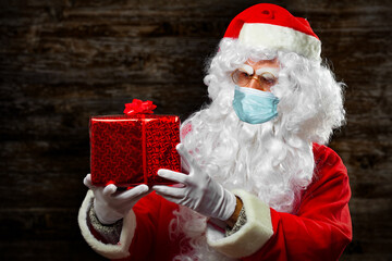 Santa Claus holding a present wearing a mask due to coronavirus pandemic