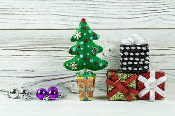 Gifts, a toy tree, Christmas decorations lie on a white wooden background.
