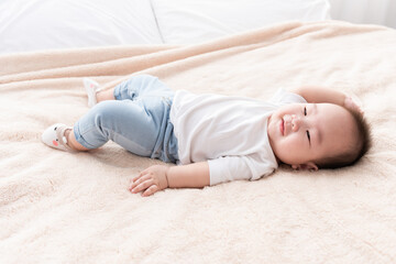 Portrait of a crawling baby on the bed. Happy asian infant in bedroom.