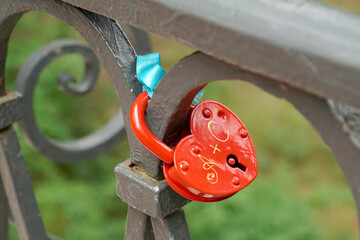 On the forged fence hangs a red lock with letters  through  the plus and symbolizes the...