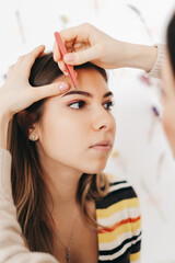 Fototapeta premium Eyebrow shaping procedure, make-up master uses tweezers to shape the eyebrows.