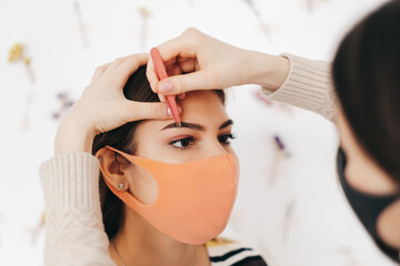 Eyebrow shaping procedure, make-up master uses tweezers to shape the eyebrows.