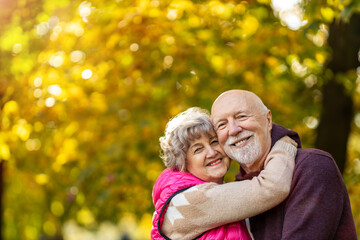 Happy senior couple spending time together in beautiful city park in autumn