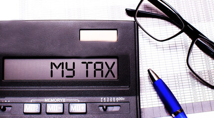 MY TAX is written in the calculator near black-framed glasses and a blue pen.