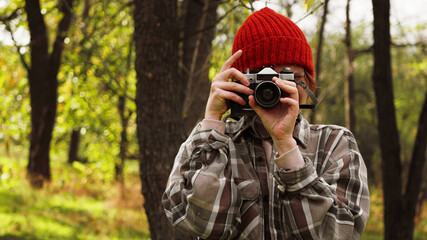 Woman taking photos on camera in the forest. Copy space. Creative photographer enjoying natural beauty 