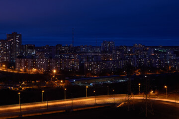 Fototapeta na wymiar night cityscape with illuminated road in the foreground and residential areas in the background