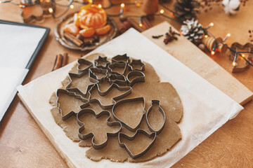 Raw gingerbread dough with metal cutters, festive decorations and lights. Christmas advent