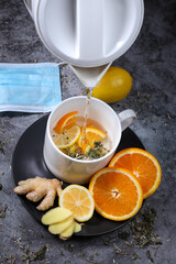 White cup of tea with lemon, ginger, orange., jam on the dark grey background. Healthcare. Vitamin cocktail.