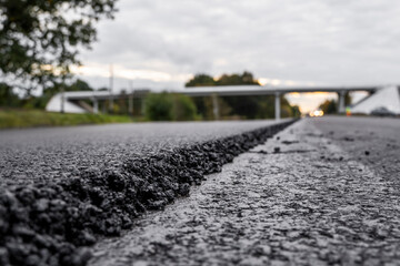 A large layer of fresh hot asphalt. Layer of asphalt raw material in a shallow depth of field. Rollers rollin fresh hot asphalt on the new road. Road construction. Construction of a new road.