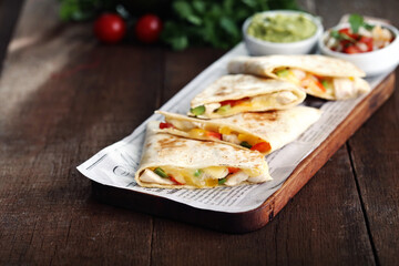 Still life on wood with chicken quesadillas, guacamole and pico de gallo