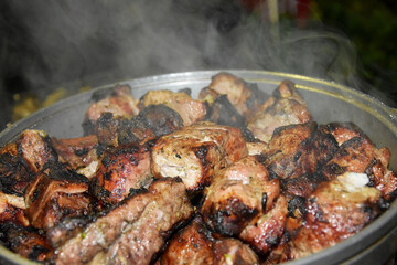 Hot pieces of fried kebabs in a saucepan, steam rises from the meat. Pieces of pork or lamb are fried on the grill.