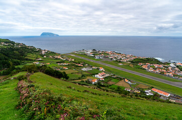 Fototapeta na wymiar Azores, island of Graciosa, view at the airport of Santa Cruz da Graciosa. th runway is near houses and church ends in the open sea. 