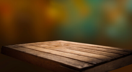 Empty wooden table top on blur light golden bokeh of cafe restaurant, bar in a dark background.