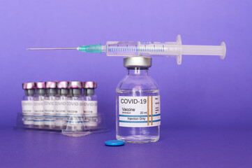 Coronavirus COVID-19 vaccine in vial and syringe, on purple background prepared for health, new...