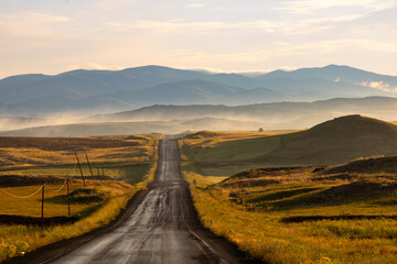 Countryroad at sunrise. Road in the field. Agricultural fields and the road.