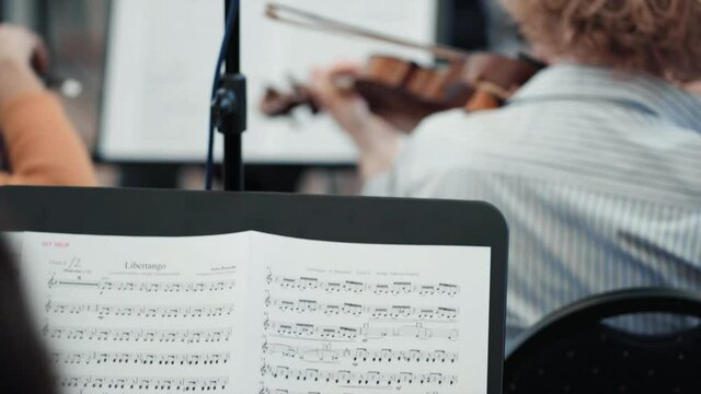 Score in the foreground and playing a violin turned on its back