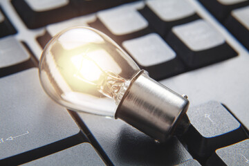 Closeup of light bulb on computer keyboard.