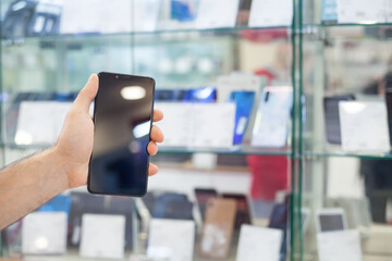 Man showing a smartphone in electronics store.