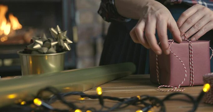 Gift workshop in a warm cozy room. Christmas decorations by fireplace. Women prepering Christmas gifts.