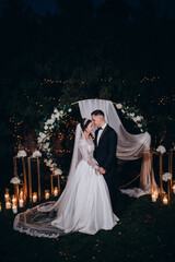 A romantic evening walk of the newlyweds against the backdrop of a flower arch.