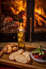Olive oil flavoured with rosemary on a wooden tray accompanied by raw olives, bread and walnuts with a Chinese base and rustic fire