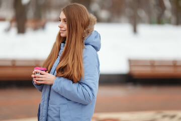 young woman walks in a winter park with coffee. winter park in the snow