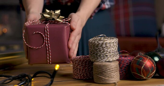 Gift workshop in a warm cozy room. Christmas decorations by fireplace. Women prepering Christmas gifts.
