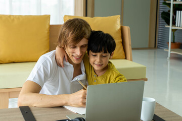Fototapeta na wymiar Young caucasian businessman and father working from home with notebook computer and taking care of little son in living room. Social distancing new normal concept.
