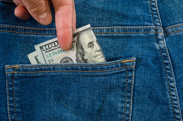 hand takes out 100 dollars from the pocket of blue jeans. Close-up.