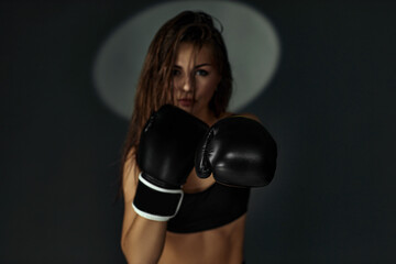 fashion photo of gorgeous sporty woman in boxing gloves punching on studio background. focus on glove