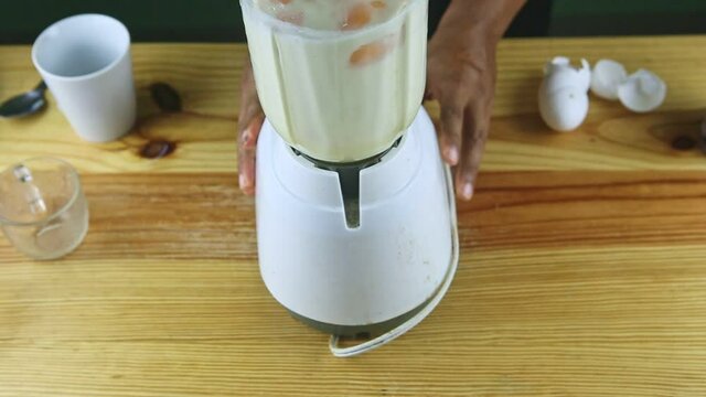 top view on man by hands holds electric blender mixing condensed milk and eggs