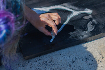 Close up of a womans hand holding a brush painting a wooden table