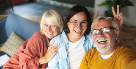 Happy elderly people with granddaughter having fun on the couch and chatting on a video call