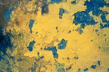 Yellow grunge wall with paint peeling off. Toned image.