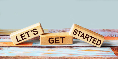 Text Let's get started on wooden blocks and colored background. Business text, motivational quote.