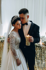 Congratulations to the newlyweds. The bride and groom are holding candles in their hands.