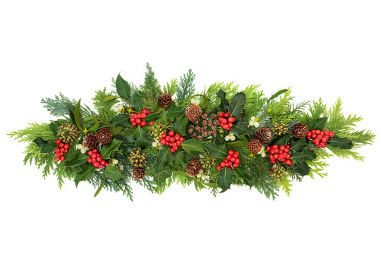 Decorative winter, Christmas & New Year floral composition with holly, ivy, mistletoe, cedar cypress fir leaves & pine cones on white background. Natural decoration for the holiday season. Flat lay.